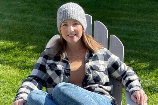 Participant Lindsay - person in flannel and a hat sitting in a chair outside