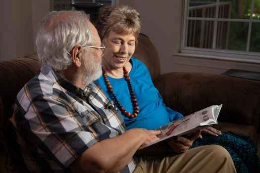 Participant Meredith - person with short blond hair sitting next to someone with short white hair on a couch, they are reading a book together