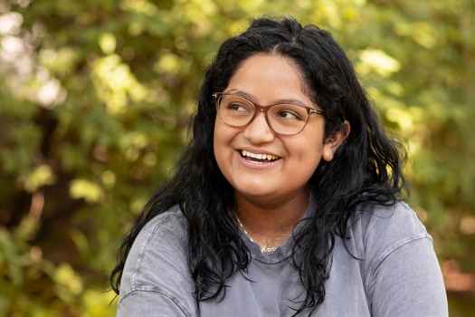 Participant Marina - person with dark hair and glasses wearing a grey t-shirt and laughing