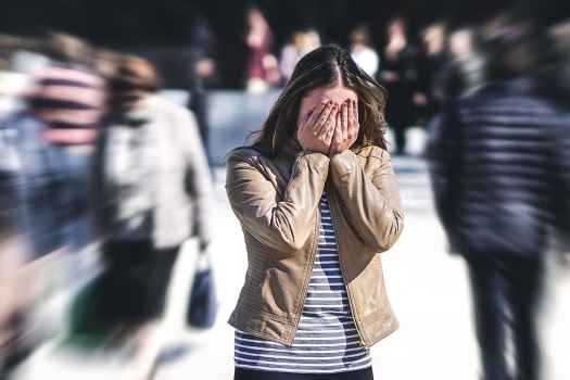 Person stands in crowd with hands over eyes