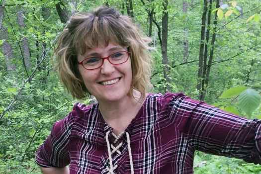 Participant Melinda - person with shoulder-length blond hair smiling in a forest