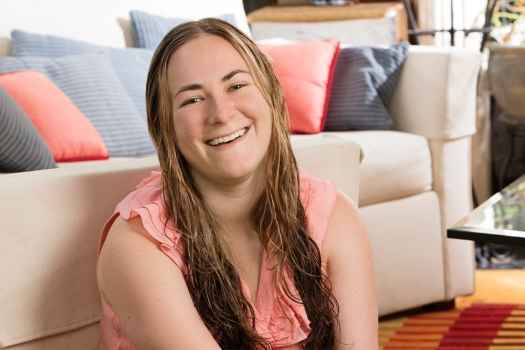 Participant Shellye - person with long wavy hair smiling in front of a couch
