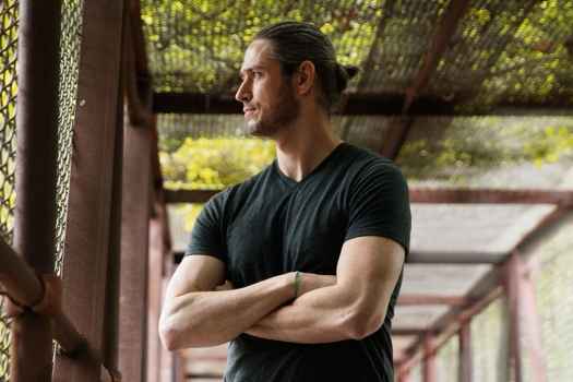 Deconstructing Stigma participant Sean - person stands in chainlink fence bridge