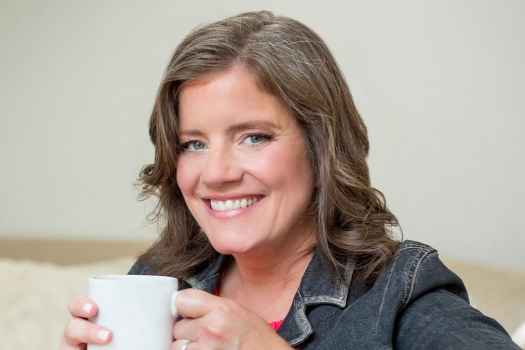 Participant Theresa - person with wavy brown hair smiling and holding a mug