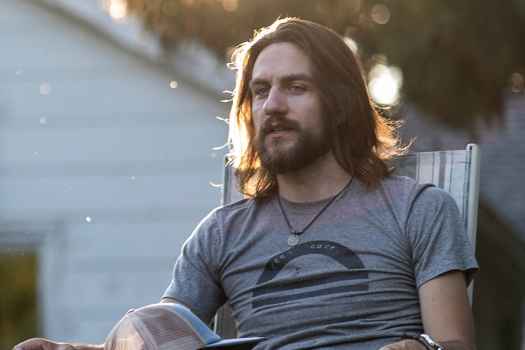 Participant Travis - person with long dark hair sitting outside