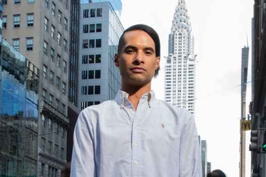 Participant Paul - person with short dark hair wearing a white shirt in front of a city skyline