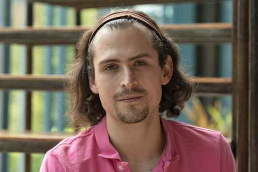 Participant Joaquín - person with shoulder-length brown hair in front of a large window