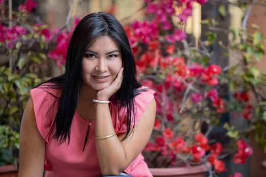 Participant Kaylee - person with long dark hair outside surrounded by pink flowers