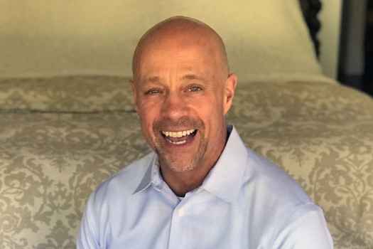 Participant David - person with facial hair smiling in front of beige fabric