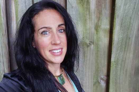 Participant Cali - person with long dark hair wearing black and smiling