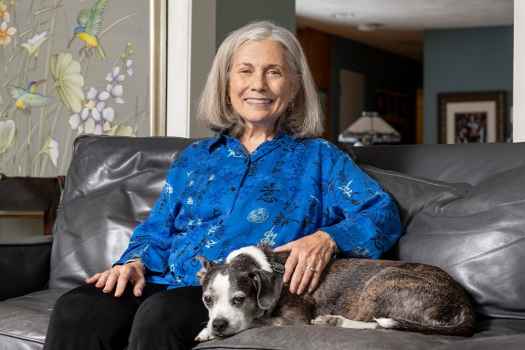 Participant Cynthia - person with grey hair sitting on a couch with a dog