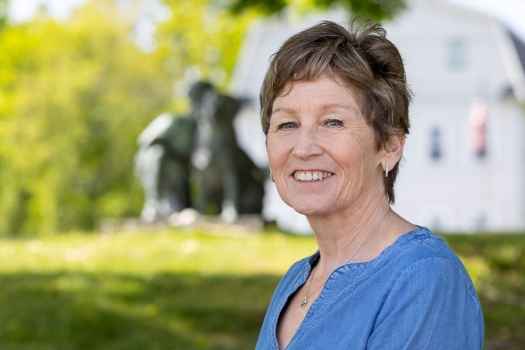 Participant Ann - person with short blond hair smiling outside, there is a statue in the background
