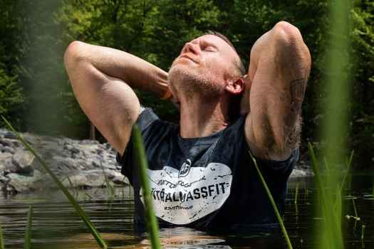 Participant Alan - person standing in chest-deep pond water tilting their head back