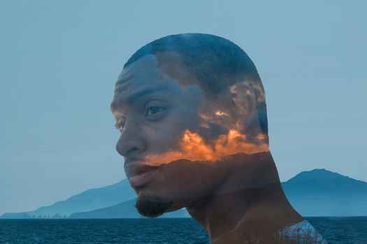Person’s head with mountain in background and vivid sunset overlaying head
