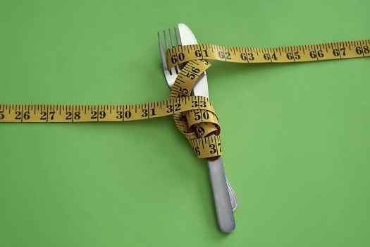Measuring tape, knife, and fork on green background