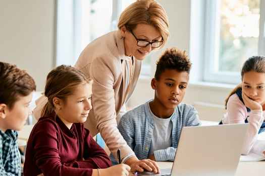 Teacher and students look at laptop