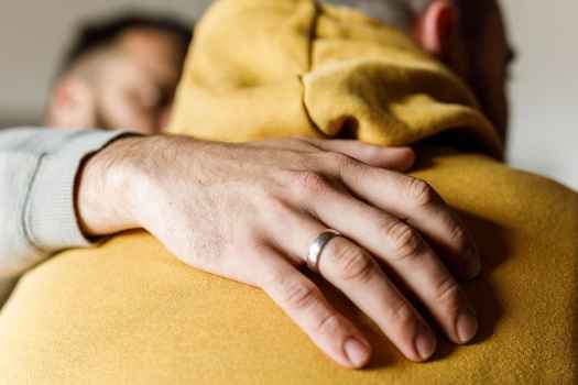 Hand on shoulder of individual in golden yellow hoodie