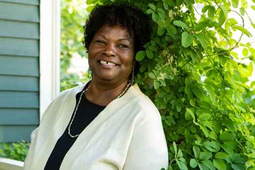 Participant Cynthia - person with dark curly hair smiling among greenery