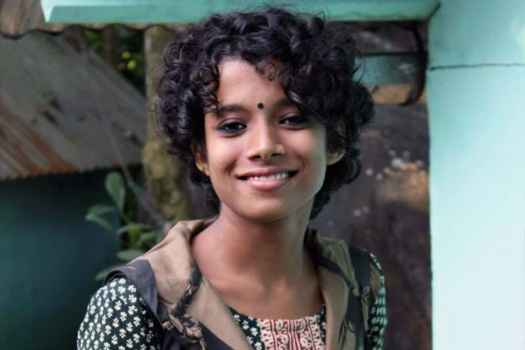 Deconstructing Stigma participant Sampurna - person with curly dark hair poses for camera
