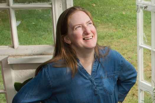 Deconstructing Stigma participant Amy - person stands in greenhouse
