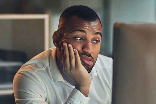 Person at computer screen with hand on chin