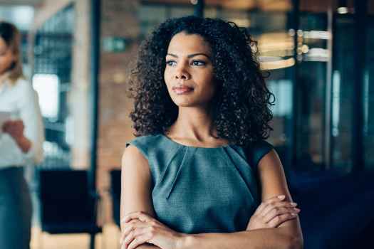Woman in office stands away from a group of colleagues