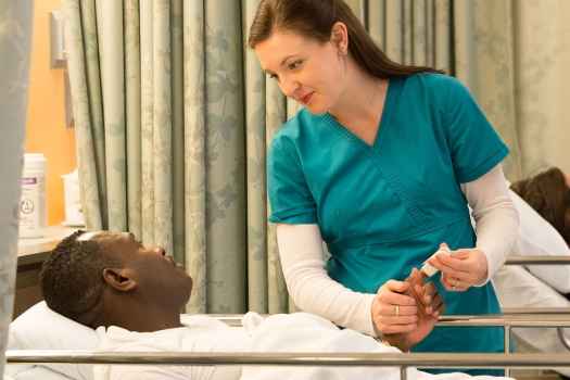 Nurse holds hand of patient in gurney