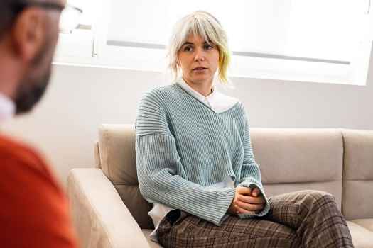 blonde woman seated, talking to a therapist