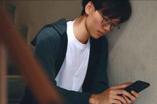 Teen sitting on stairs looking at his phone