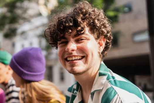 Person with short curly hair smiling