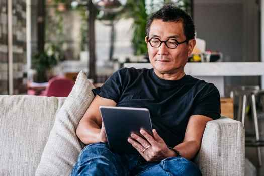 Man sits on couch reading tablet