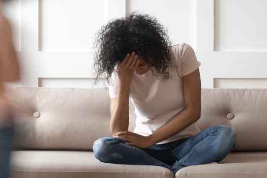 Stressed out woman with hand on head sitting on a couch