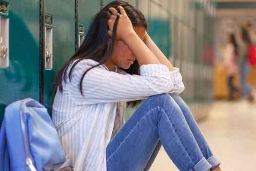 Girl sits against school lockers