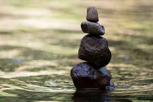 Four rocks stacked into a tower in a body of water