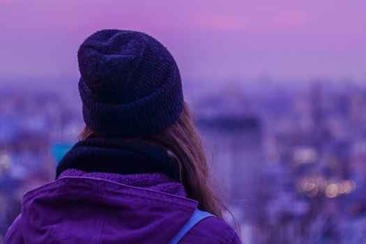 hipster girl looking out into the city at dusk