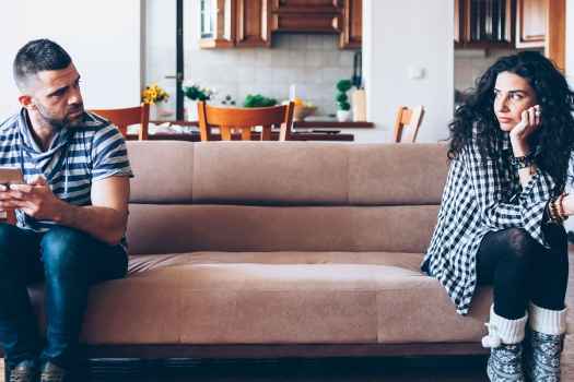 A couple looking angrily at each other while sitting on a couch