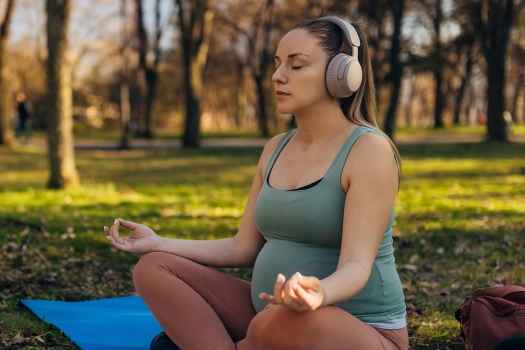 Pregnant person meditating on yoga mat outside