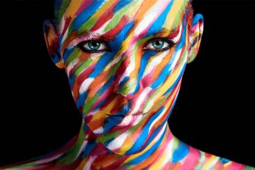 Head with painted face of colorful stripes on black background