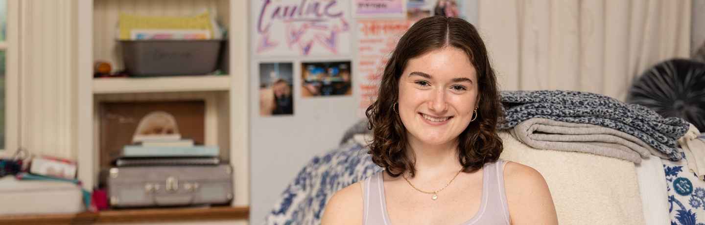 Participant Caroline - person with short brown hair wearing light purple and smiling in front of a bookshelf