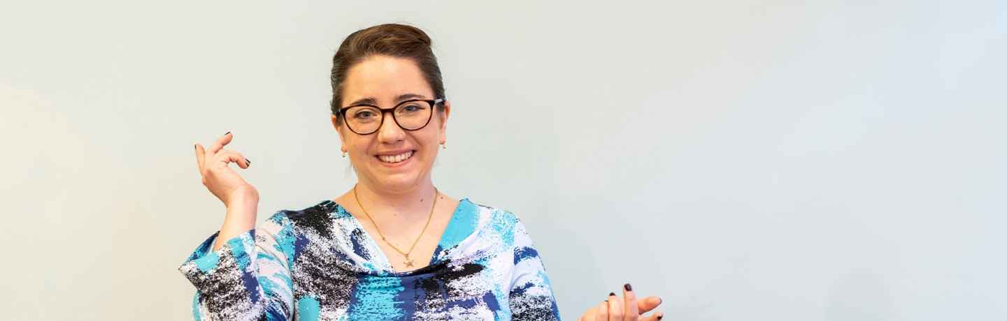 Participant Francisca - person with dark hair and glasses smiling in front of a whiteboard