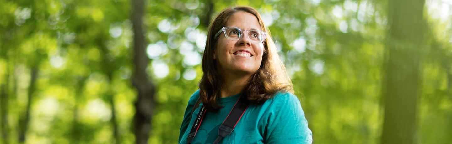 Participant Marlena - person with brown hair and glasses with a camera in the forest
