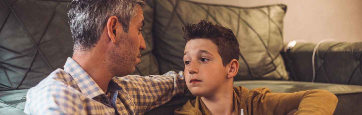 Man and boy sitting on the floor in front of a couch
