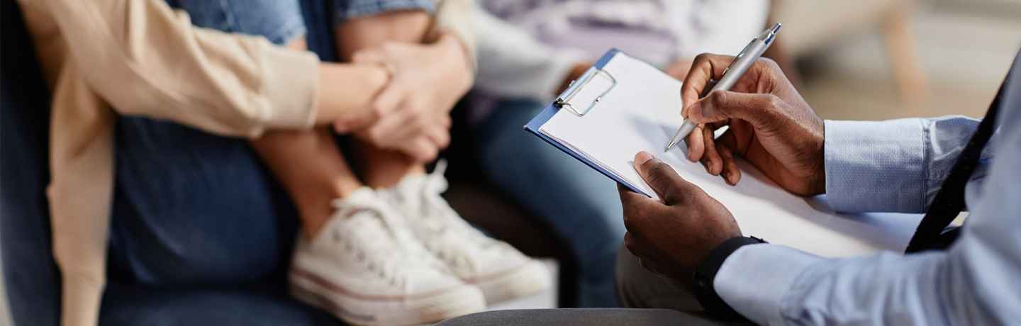 therapist writing on clipboard with child in background