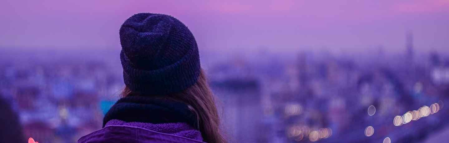 hipster girl looking out into the city at dusk