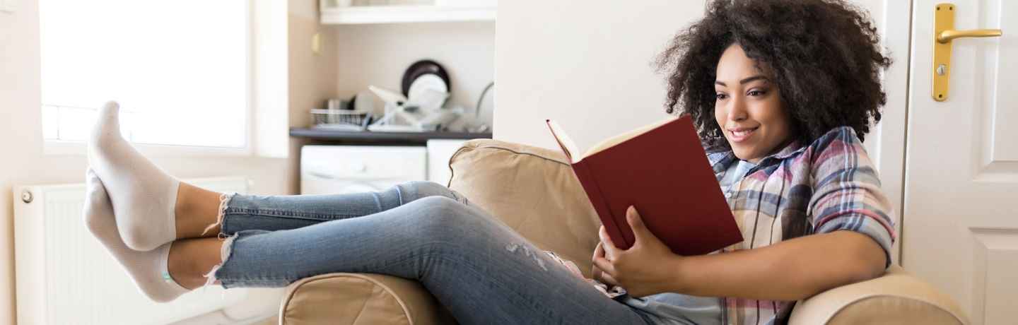 woman sitting in lounge chair reading a book