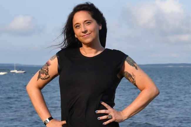 Participant Leslie - person with long dark hair smiling in front of a body of water
