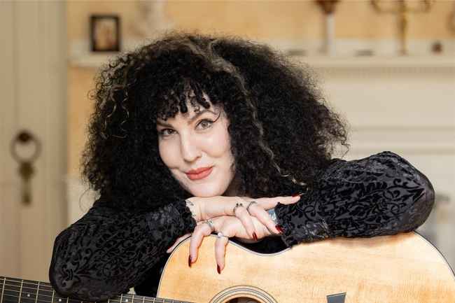 Participant Anne leaning on an acustic guitar