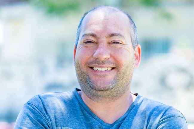Deconstructing Stigma participant Eitan - person sits outside green plants in the background