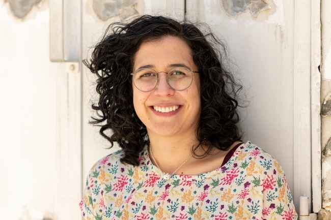 Deconstructing Stigma participant Jimena - Person in flowery shirt leans agains metal wall