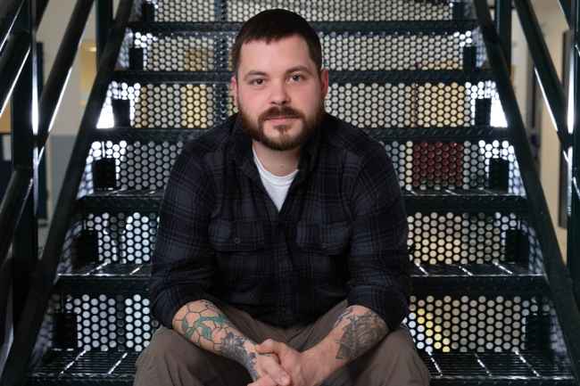 Participant Ron - person in plaid shirt sitting on staircase